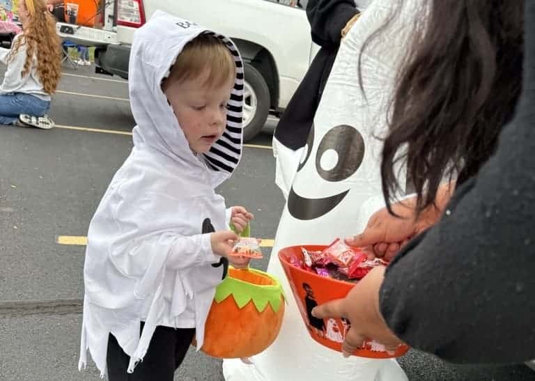 young child in a halloween custome taking a treat from a bowl