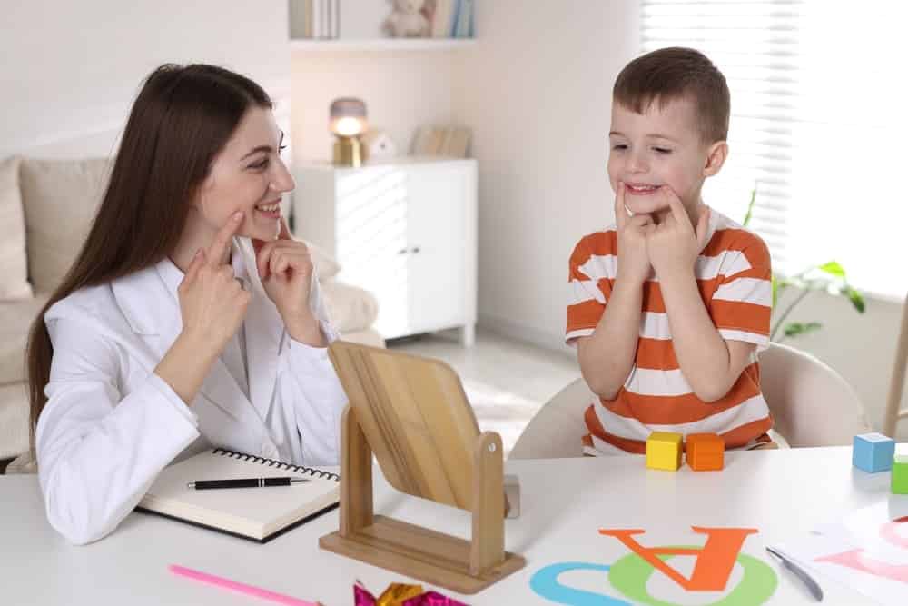 Speech therapist working with little boy indoors